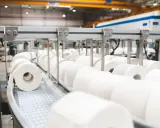 Rzędy rolek papieru toaletowego na linii produkcyjnej. Nowoczesna produkcja papieru w Polsce.