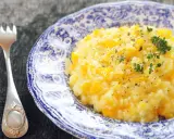 Pyszny, kremowy ryż do risotto z kawałkami dyni, posypany świeżym tymiankiem i pieprzem. Obok leży elegancki widelec.
