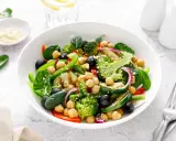 Ensalada de legumbres vibrante con garbanzos, brócoli, espinacas, aceitunas negras y pimientos verdes.