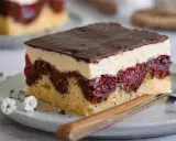Ein Stück Donauwelle-Kuchen mit Schokoladenglasur, Sahne und Kirschen. Dieses Rezept ist ein Klassiker.