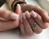 Dłonie z idealnym french manicure. Paznokcie prostokątne w delikatnym różu z białymi końcówkami, ozdobione srebrnym pierścionkiem.