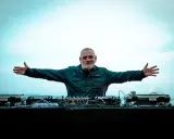 DJ Ralf, un vero patrimonio della musica elettronica, con le braccia aperte davanti alla sua consolle, pronto a far ballare il mondo.