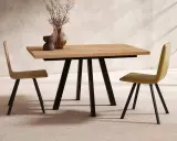 Mesa comedor extensible de madera con patas metálicas negras, ideal para ampliar el espacio. Dos sillas modernas flanquean la mesa.