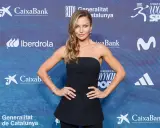 Anna Lewandowska w czarnej, asymetrycznej kreacji prezentuje elegancki anna lewandowska styl na tle sponsorów gali.