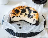 Ein cremiger Oreo Kuchen mit einem dunklen Keksboden, dekoriert mit ganzen und zerbrochenen Oreos.