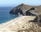 Sonnige Playa de los Muertos mit türkisfarbenem Meer, Felsen und vielen Sonnenanbetern.