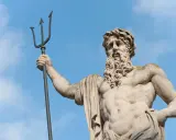 Statue de Poseidon dieu des mers, tenant son trident, sous un ciel bleu.