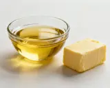 Ein Stück Butter und eine Schüssel mit Öl, bereit für die Zubereitung von Transfetten.