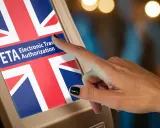 Dłoń dotyka ekranu z flagą Wielkiej Brytanii i napisem ETA - Electronic Travel Authorization.
