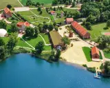 Widok z lotu ptaka na ośrodek SPA nad jeziorem z budynkami, plażą i kortem tenisowym.