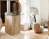 Arredamento vintage casa: poltrone soffici, tavolini in travertino e vetro, lampade di design e specchi antichi creano un'atmosfera accogliente.