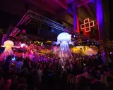En livlig nattklubb i Stockholm med uppblåsbara maneter, discokulor och en stor publik som dansar under neonljus.