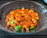 Pyszne gnocchi z sosem pomidorowym i świeżą bazylią, podane w szklanej misie. Idealne danie dla miłośników włoskiej kuchni.