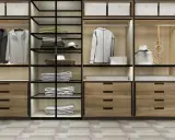 Un moderno armario empotrado con puertas de cristal y madera, organizado con ropa doblada, colgada y accesorios.