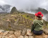 Kobieta w czerwonym kapeluszu podziwia Machu Picchu. Czy w Peru jest bezpiecznie? Tak, to bezpieczna podróż do serca Inków.