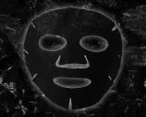 Maschera al carbone, con i suoi benefici, appare come un volto misterioso incorniciato da texture scure e profonde.