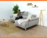 Mujer colocando cojines en chaise longue gris. Un estilo acogedor para tu salón.