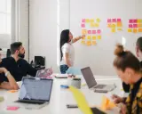 Zespół dyskutuje przy tablicy z kolorowymi karteczkami. Co to znaczy "there"? To miejsce, gdzie rodzą się pomysły.