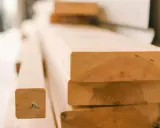 Stapel von unbehandelten Holzbrettern, bereit für den Bau eines Dach-Ringbalkens.