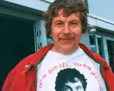 Staffan Westerberg, känd för sina filmer och tv-program, ler i en röd jacka över en t-shirt med hans eget ansikte och texten "Det är ditt fel, Staffan Westerberg".