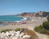 Sonniger Tag am playa de guadalmar mit Menschen, die sich am Strand sonnen und im türkisfarbenen Meer schwimmen.