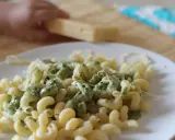 Pyszny makaron ze szpinakiem i parmezanem, gotowy do podania. Dziecko pomaga w przygotowaniu.