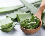 Aloe vera a fette in un cucchiaio di legno, pronte per scoprire come applicare aloe vera sulla pelle per un sollievo naturale.