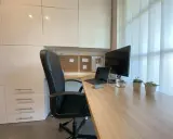 Un coin bureau moderne et fonctionnel pour aménager votre espace de travail. Chaise noire, bureau en bois, écran, ordinateur portable et plantes vertes.