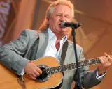 Artysta w szarym garniturze gra na gitarze i śpiewa. Kto śpiewał kolorowe jarmarki?