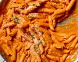 Penne alla vodka w kremowym sosie pomidorowym, posypane parmezanem i bazylią.