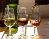 Drei Gläser mit Sherry, die die Vielfalt der sherry Herkunft zeigen. Ein helles, ein dunkles und ein drittes, das gerade eingeschenkt wird.