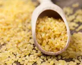Kasza bulgur na drewnianej łyżce. Niska kasza bulgur indeks glikemiczny sprawia, że jest idealna dla diabetyków.