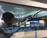 Un trabajador aplica **silicona estructural** en una junta de ventana.