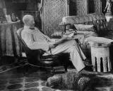 A man reads in a plush armchair, a dog sleeps nearby. The opulent room hints at the grandeur of the Rothschild art collection.