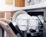 Cesta de lavavajillas llena de platos blancos. Aprende como limpiar el lavavajillas para que tus vajillas queden relucientes.