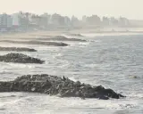 Olas rompen contra una escollera de rocas, protegiendo una ciudad costera. El escollera significado es claro: barrera contra el mar.