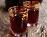Dwa kieliszki z rubinową, szybką nalewką z wiśni na spirytusie, ozdobione złotymi wzorami.