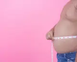 Mężczyzna mierzy swój duży brzuch. Miarka pokazuje ponad 37 cm.