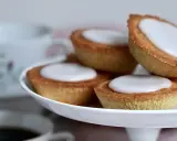 Små, gyllene mazariner med vit glasyr på ett tårtfat. Perfekt till fikat, här är ett enkelt mazariner recept.