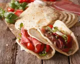 Piadina romagnola, un piatto tipico di Rimini, farcita con prosciutto crudo, pomodorini e rucola.