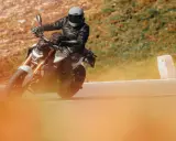 Motociclista con casco y chaqueta de cuero en una moto deportiva, disfrutando de la carretera. Ideal para quienes buscan el permiso conducir A1.
