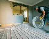 Instalator układa rury do ogrzewania podłogowego z sieci miejskiej.