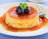 Delicioso flan de queso con cuajada, cubierto de caramelo líquido y adornado con arándanos y menta.