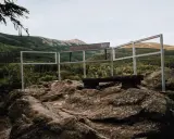 Kamienna platforma widokowa na szczycie, z ławką i barierkami, oferuje panoramę gór porośniętych lasem. To idealne miejsce na odpoczynek i podziwianie krajobrazu, niczym z legend o kruczych skałach.
