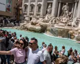 Foule de touristes admirant la fontaine de Trevi, la fontaine de l'amour à Rome, prenant des selfies devant les statues majestueuses et l'eau turquoise.