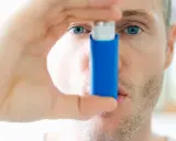 Mann mit blauen Augen hält einen blauen Inhalator, ein reliever asthma.