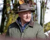 Klaus Balkenhol, ein älterer Herr mit Hut und Steppjacke, blickt nachdenklich in die Ferne.