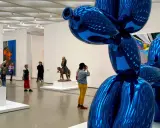 Visitors admire a giant blue balloon dog sculpture in a modern art gallery, a highlight among the top art galleries in the world.