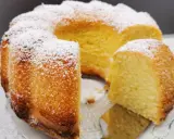 Wilgotna babka z ajerkoniakiem, oprószona cukrem pudrem, prezentuje się apetycznie na szklanej paterze.