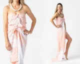Modella mostra come indossare un pareo con fantasia tropicale, annodato in vita e al seno, con una collana di conchiglie.